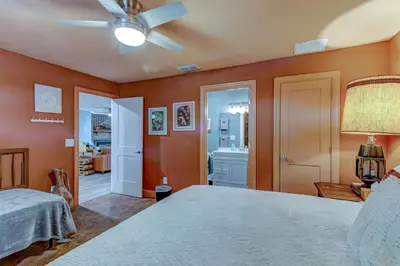 a bedroom with orange walls and a bed and a bathroom at Happy Palette Home Close to downtown Fenced yard in Sanford