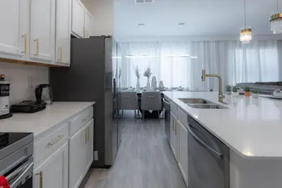 a kitchen with white countertops and a kitchen with a table at Brand New Home 8 BedroomsPoolSleeps 26 in Kissimmee