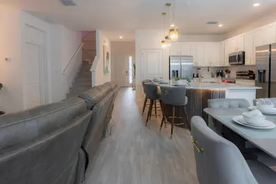 a living room and kitchen with a couch and a table at Brand New Home 8 BedroomsPoolSleeps 26 in Kissimmee