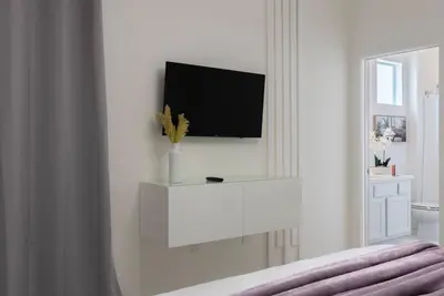 a white bedroom with a tv on a wall at Brand New Home 8 BedroomsPoolSleeps 26 in Kissimmee