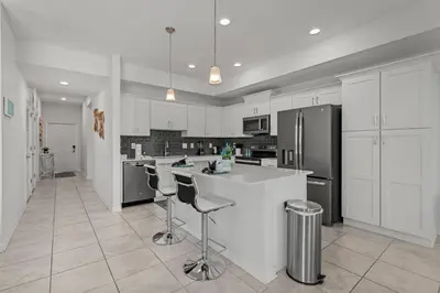 a kitchen with white cabinets and stainless steel appliances at Cozy & Stylish 2BR Condo Prime Storey Lake Spot in Kissimmee