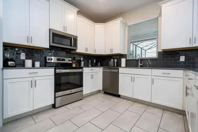 a kitchen with white cabinets and black appliances at Villa 6Q Disney Style c/ Piscina e Game Room in Kissimmee