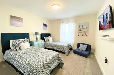 a bedroom with two beds and a blue chair at Casa 4Q com Piscina Aquecível — Storey Lake in Kissimmee