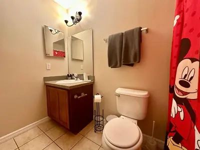 a bathroom with a toilet and a sink and a mirror at Grand Panoramic 3BR Townhouse Near Disney Parks in Kissimmee