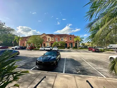 a black car parked in a parking lot in front of a house at Grand Panoramic 3BR Townhouse Near Disney Parks in Kissimmee