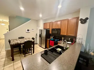 a kitchen with a table and a refrigerator at Grand Panoramic 3BR Townhouse Near Disney Parks in Kissimmee