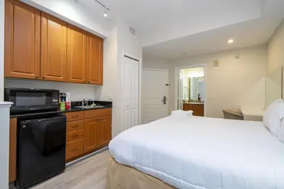 a bedroom with a large white bed and a kitchen at Near Universal Parks Cozy Apartament at The Point in Orlando