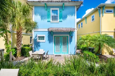 a blue house with a table in front of it at Palm Tree Paradise Cottage Near Disney With Margaritaville Resort & Island H20 Waterpark Access - 3087Pi in Orlando