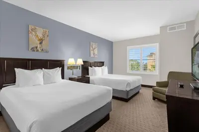 a hotel room with two beds and a flat screen tv at Stylish Queen Suite near Disney Sleeps at 4 in Orlando