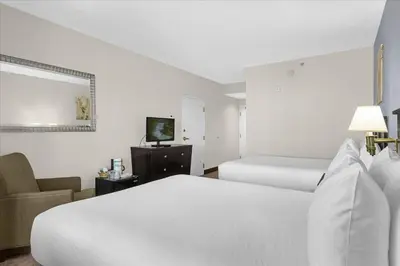 a hotel room with two beds and a chair at Stylish Queen Suite near Disney Sleeps at 4 in Orlando