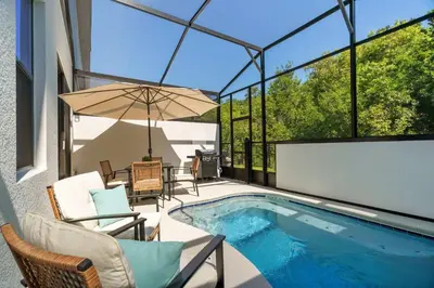 a swimming pool with chairs and an umbrella on a patio at Luxury Paradise in Orlando Best Location in Orlando
