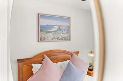 a framed picture above a bed with pink and grey pillows at Family favorite Disney pool home in Kissimmee