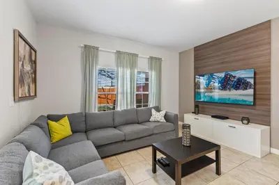 a living room with a gray couch and a tv at 8893 Candy Palm Road in Kissimmee