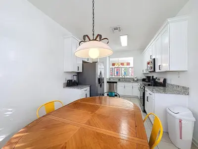 a kitchen with a wooden table and yellow chairs at Free Water Park-Close to Disney-3 King-POOL-SPA in Orlando