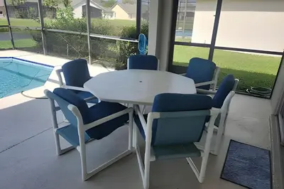 a white table with blue chairs and a pool at Lake View Pool Home near Disney and Shoppings in Kissimmee