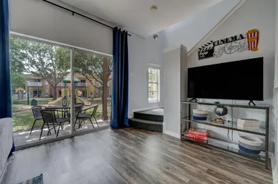 a living room with a television and a table with chairs at Family Retreat Near Disney in Emerald Island in Kissimmee