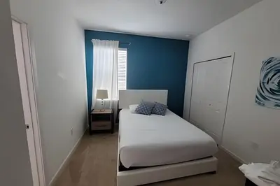 a bedroom with a white bed and a blue wall at Fantastic Large Pool,Sonoma Resort in Kissimmee