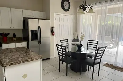 a kitchen with a table and chairs and a refrigerator at Emerald Island Resort : Pool & Games Room in Kissimmee