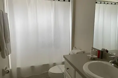 a white bathroom with a toilet and a sink at Emerald Island Resort : Pool & Games Room in Kissimmee