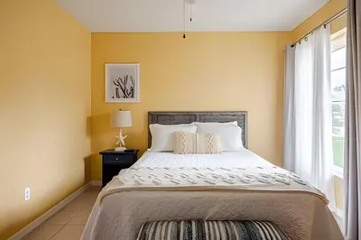 a bedroom with a large bed and a window at 10 Minutes to Disney Pool Home *Renovated* in Kissimmee