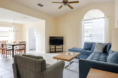 a living room with a blue couch and a table at 10 Minutes to Disney Pool Home *Renovated* in Kissimmee