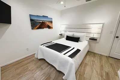 a white bedroom with a large bed and a painting at Lakeside Pool Home, Games close to Disney & Malls in Kissimmee