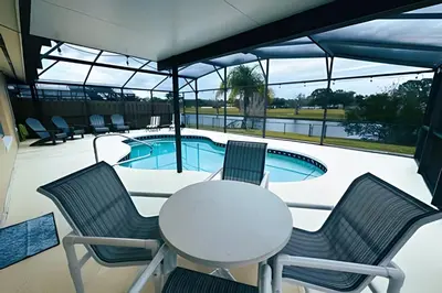 a patio with a table and chairs and a swimming pool at Lakeside Pool Home, Games close to Disney & Malls in Kissimmee