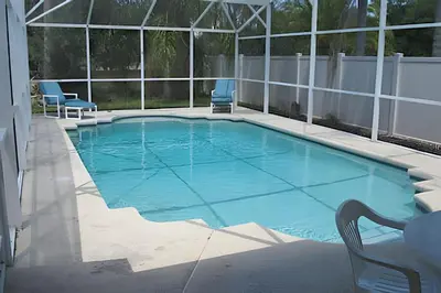 a swimming pool with two blue chairs in a building at 10 Minutes to Disney! Pool Home Large Lot in Kissimmee