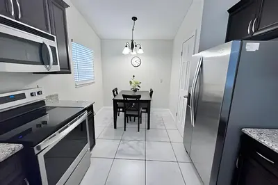 a kitchen with a table and a stainless steel refrigerator at 10 Minutes to Disney! Pool Hom, Large Backyard in Kissimmee