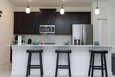 a kitchen with a white counter and two bar stools at Luxurious Home w/ Pool Near Disney in Kissimmee