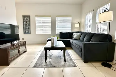 a living room with a black couch and a table at Bella Vida Resort Pool Home near Disney in Kissimmee