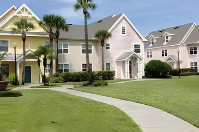 a house with palm trees and a sidewalk at Runaway Beach Club Condo near Disney in Kissimmee