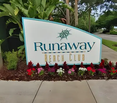 a sign for the runaways beach club with flowers at Runaway Beach Club Condo near Disney in Kissimmee