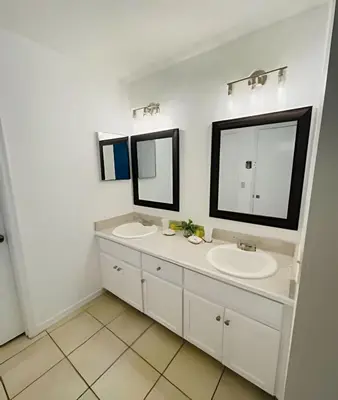 a bathroom with two sinks and two mirrors at Huge Lot, Private Pool Home Centrally Located in Kissimmee