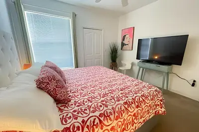 a bedroom with a bed and a flat screen tv at Cozy & Bright Condo in Legacy Dunes near Disney in Kissimmee