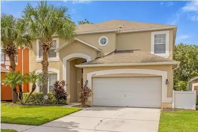 a house with a garage and palm trees at 2767LKD-Emerald Island Resort home in Kissimmee