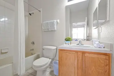 a white bathroom with a toilet and a sink at Resort Access and Great Location in Orlando