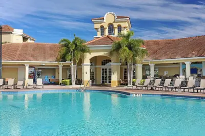 a pool in front of a house with chairs and a building at Tropical Lakeview Condo w. Vegas Game Room - 1014 in Orlando