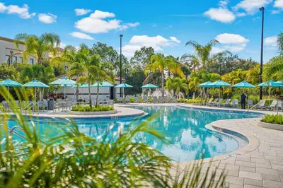 a swimming pool at a resort with blue umbrellas at Luxury Lakeview Penthouse, Vista Cay Orlando 1025 in Orlando