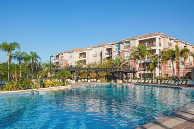 a large swimming pool with palm trees and buildings at Stunning Epic Universe Condo - Vista Cay Resort - 2016 in Orlando