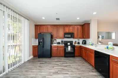 a kitchen with wooden cabinets and a black refrigerator at Beautiful Family Townhome, Near The Parks - 4032 in Orlando