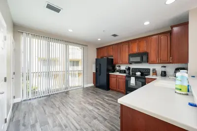 a kitchen with wooden cabinets and a black refrigerator at Beautiful Family Townhome, Near The Parks - 4032 in Orlando