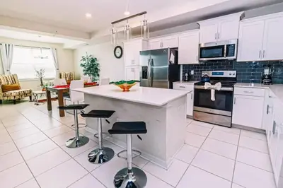 a kitchen with white cabinets and a island with bar stools at Conforto e Lazer a 7km da Disney – 2 Quartos in Kissimmee
