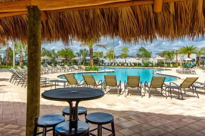 a patio with a table and chairs and a pool at Conforto e Lazer a 7km da Disney – 2 Quartos in Kissimmee