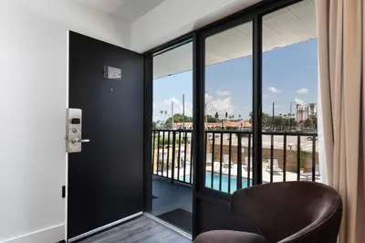a room with a balcony with a chair and glass doors at The Vietta Hotel in Kissimmee