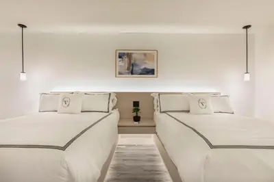 two beds in a room with white walls at The Vietta Hotel in Kissimmee
