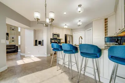 a kitchen with blue bar stools at a counter at Bay Pointe Pool Home Near Parks in Kissimmee
