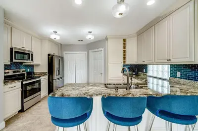 a kitchen with a counter with blue chairs around it at Bay Pointe Pool Home Near Parks in Kissimmee