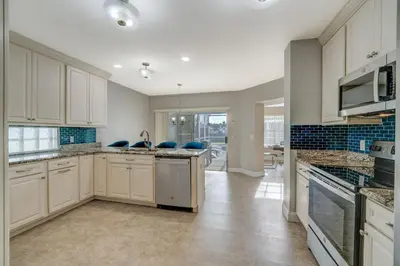 a large kitchen with white cabinets and blue tiles at Bay Pointe Pool Home Near Parks in Kissimmee