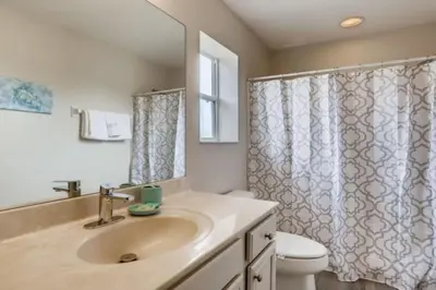 a bathroom with a sink and a toilet and a mirror at Lakefront 6BR Resort Pool Home Near Disney World in Kissimmee